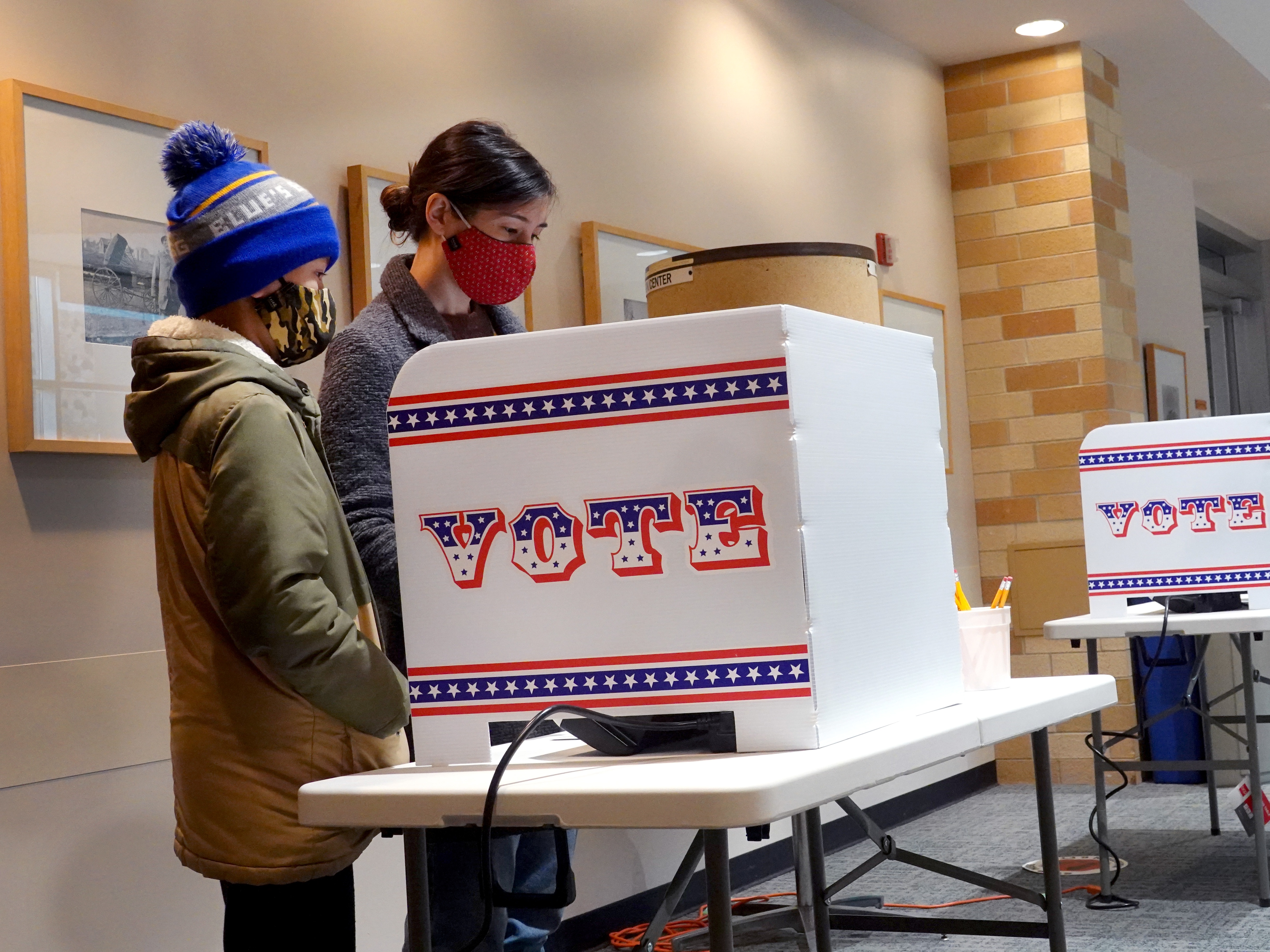 caption: Marie Guenther votes at the Bay View Library with her son in October 2020 in Milwaukee, Wis., considered a battleground state.