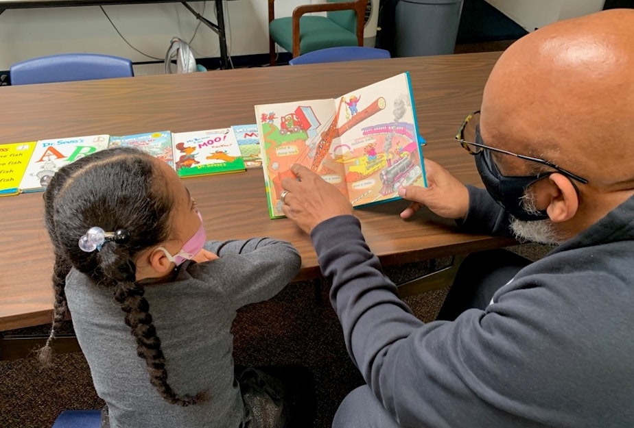 caption: Gerald Donaldson, a family support worker at Leschi Elementary in Seattle, reads to a kindergartener during the Covid-19 pandemic.