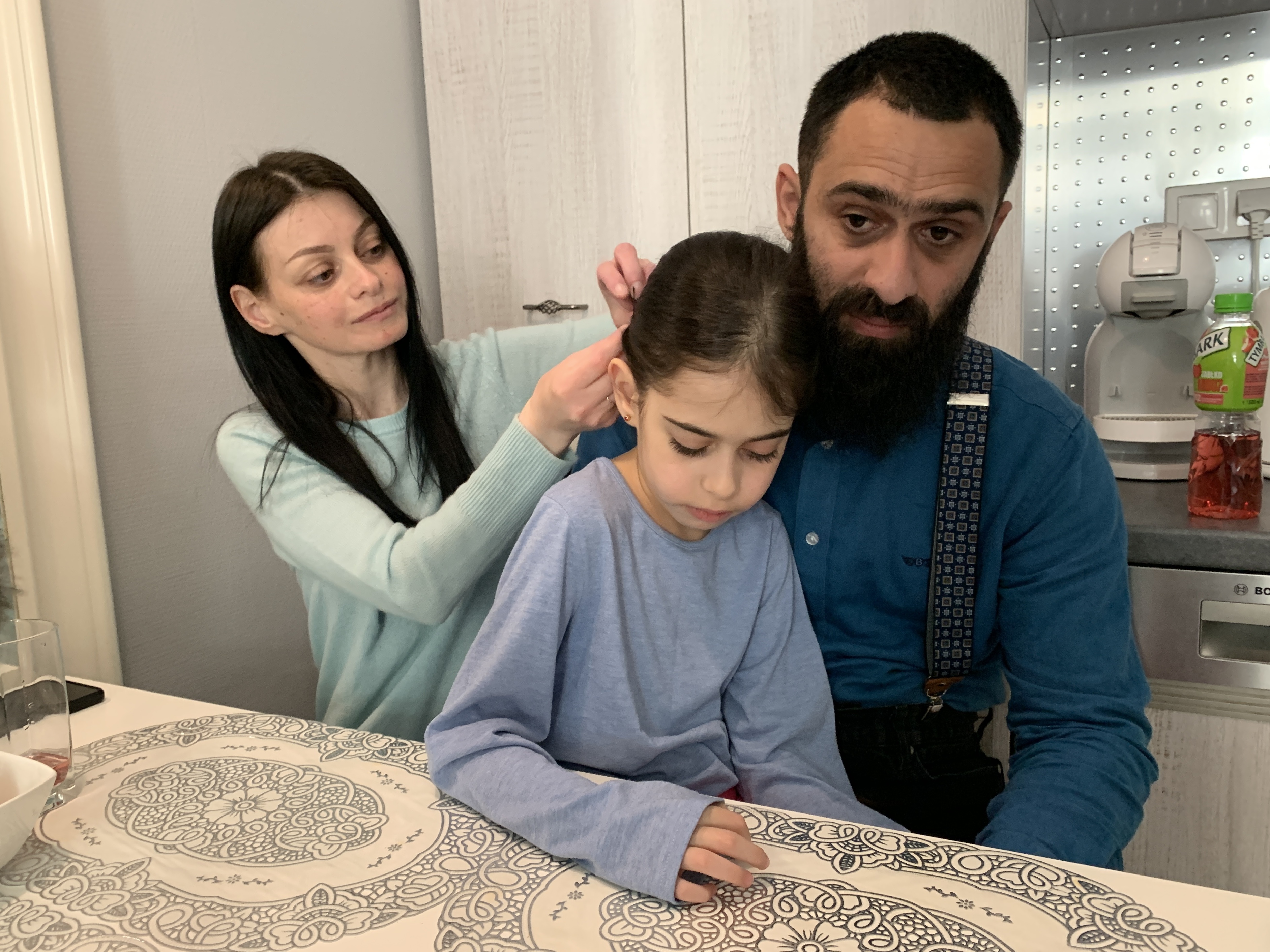 caption: Olena Kopchak, her husband, Albert Kodua, and their eight-year-old daughter, Yana, are staying in a small 250-square-foot apartment in Warsaw, Poland. They hope to make it to the United States.