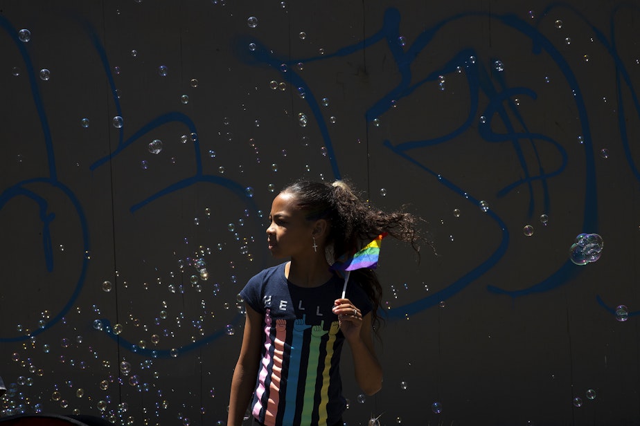 caption: Mariah Jones, 10, watches Seattle’s Pride Parade on Sunday, June 25, 2023, in downtown Seattle.