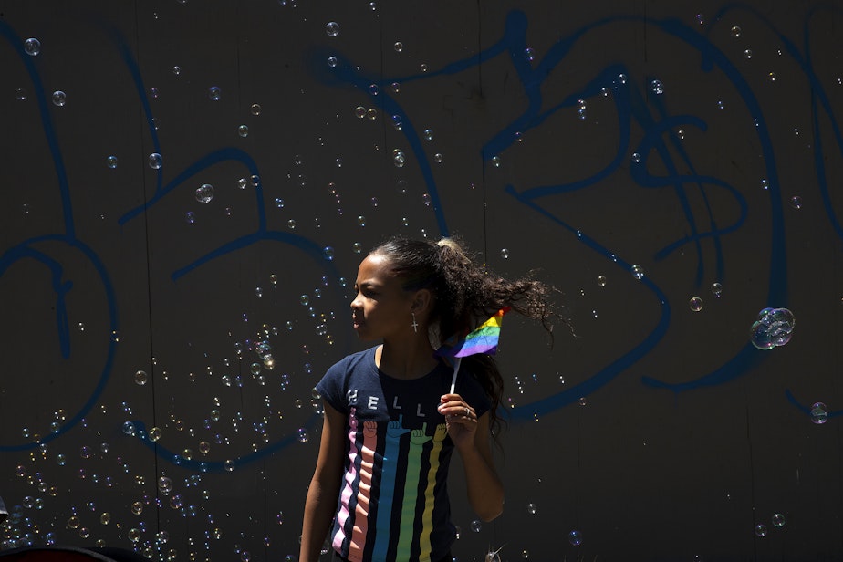 caption: Mariah Jones, 10, watches Seattle’s Pride Parade on Sunday, June 25, 2023, in downtown Seattle. 