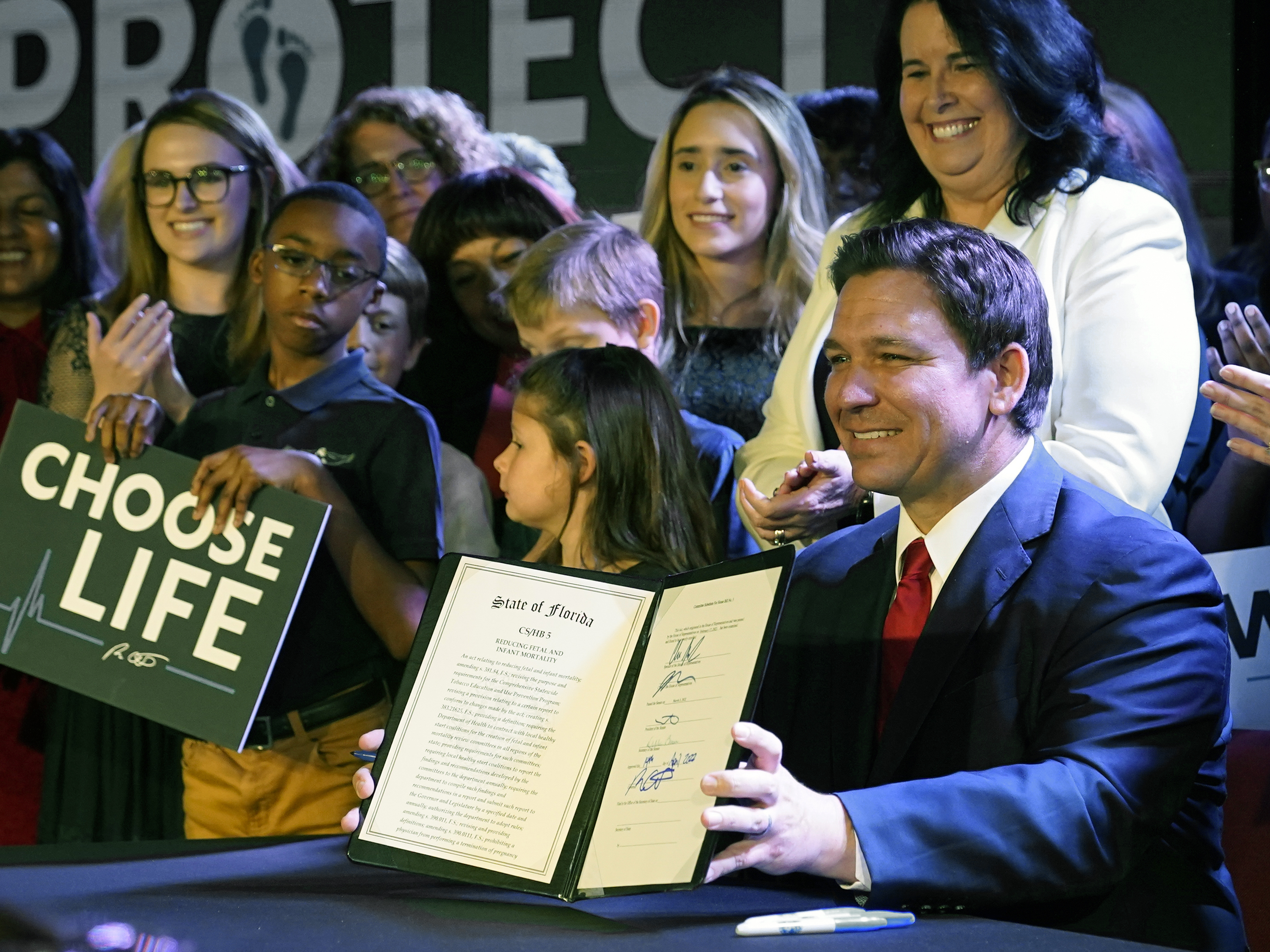 caption: Florida Gov. Ron DeSantis holds up a 15-week abortion ban law after signing it on April 14, in Kissimmee, Fla. A synagogue claims in a lawsuit that the law violates religious freedom rights of Jews in addition to the state constitution's privacy protections.