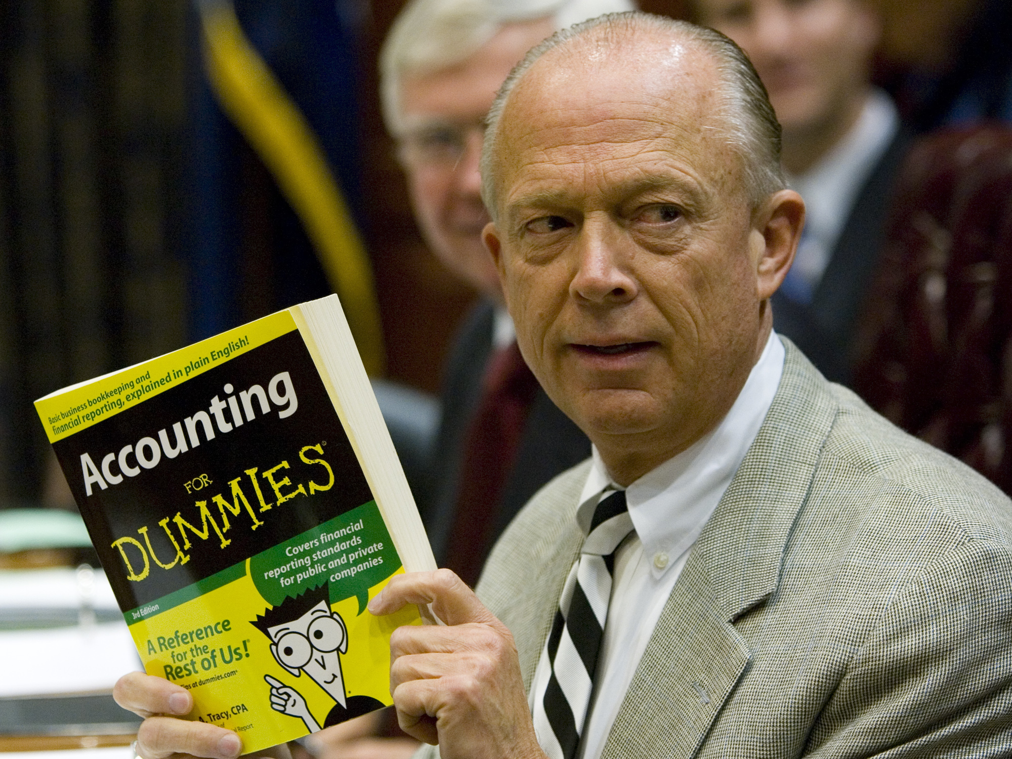 caption: South Carolina Comptroller General Richard Eckstrom holds up a book he wanted to present to his new chief of staff James Holly during his introduction a meeting on Aug. 13, 2009, in Columbia, S.C. Eckstrom is stepping down from his post after a $3.5 billion accounting error.