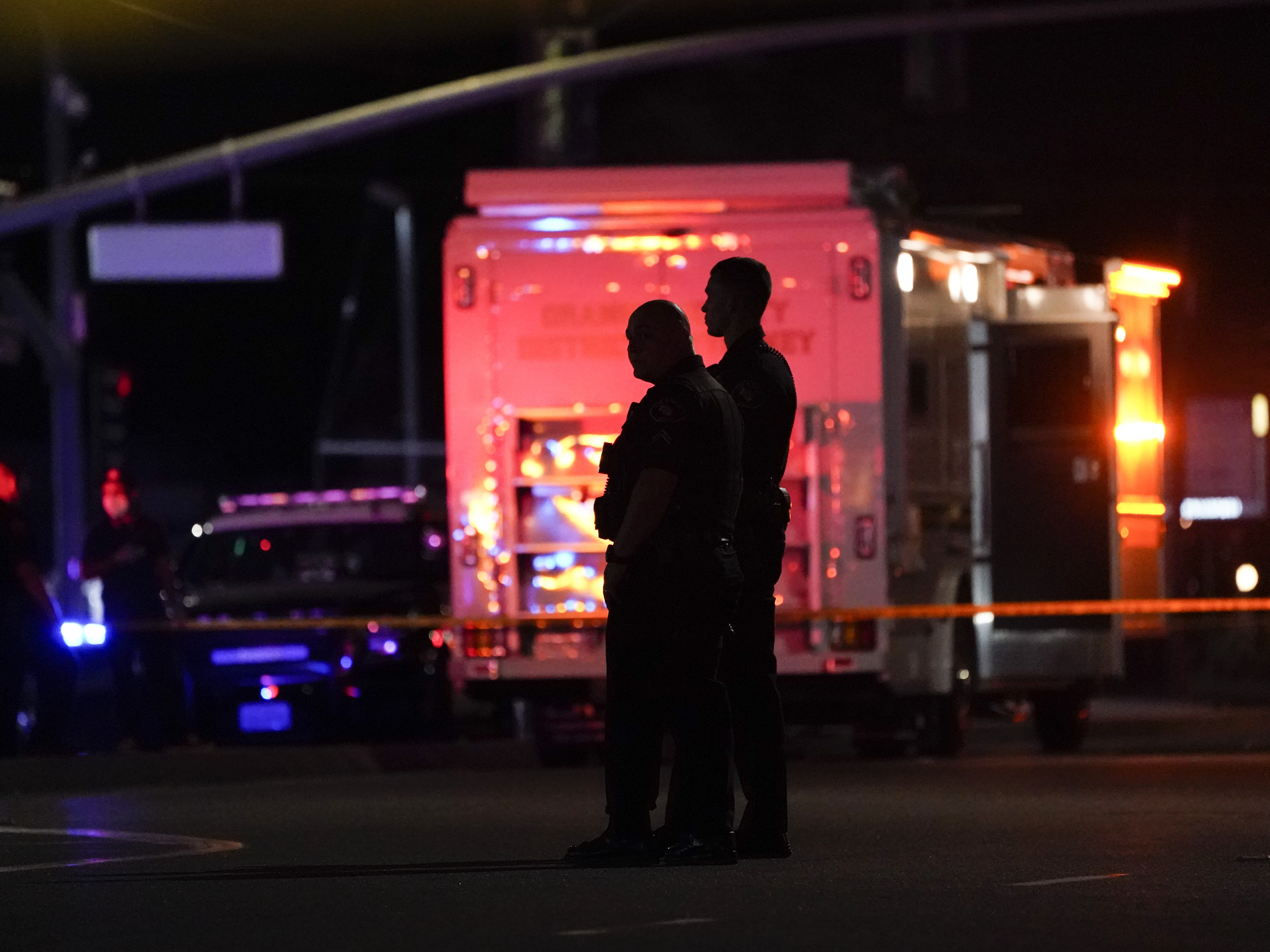 caption: Two police officers stand outside an office building where a shooting occurred in Orange, Calif., Wednesday, March 31, 2021. The shooting killed several people, including a child, and injured another person before police shot the suspect, police said.
