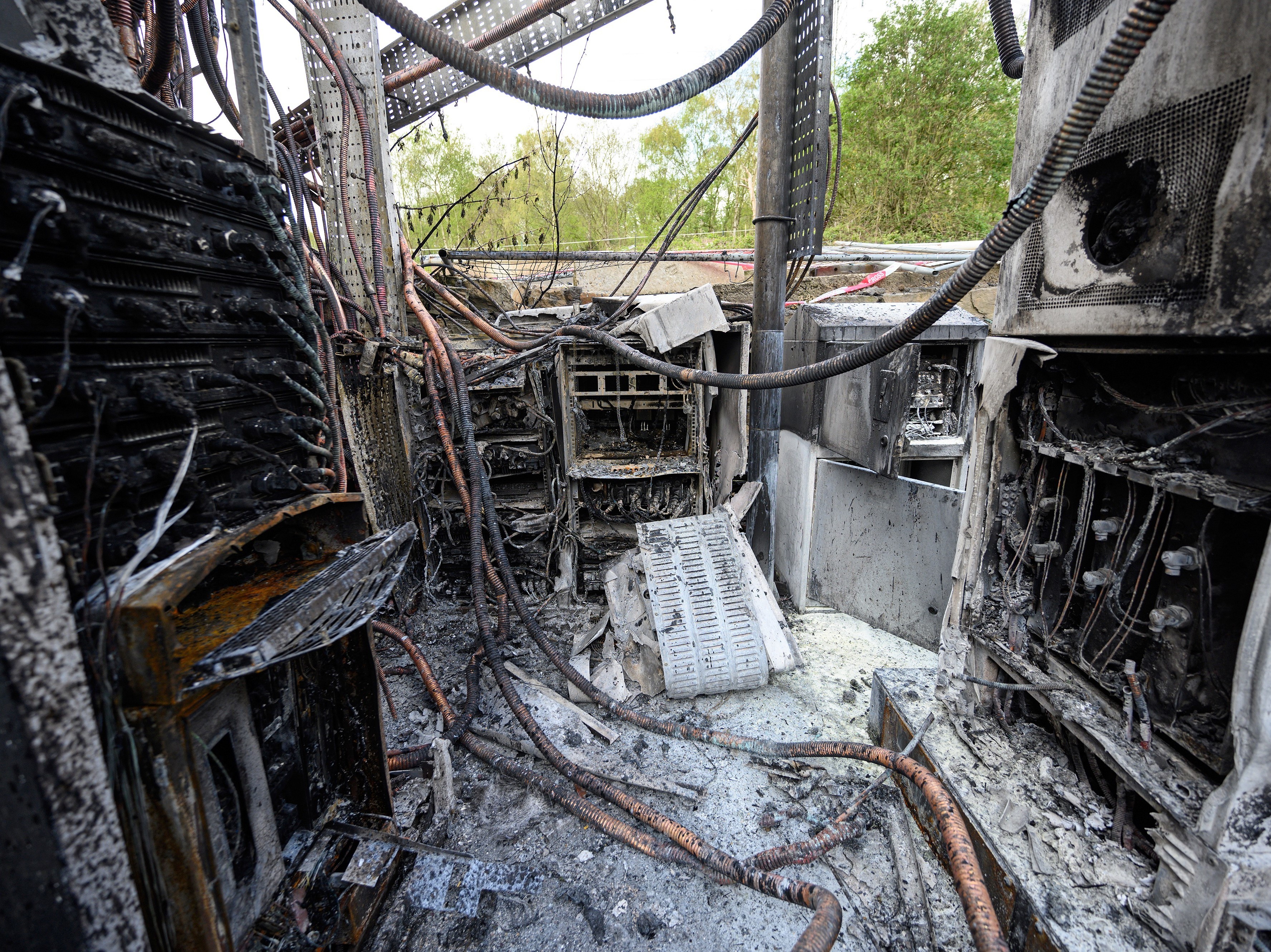 caption: Cabling and telecommunications equipment is damaged after a fire in April in Huddersfield, England. The fire came as other cellphone towers burned amid conspiracy theories linking 5G mobile technologies to the coronavirus.