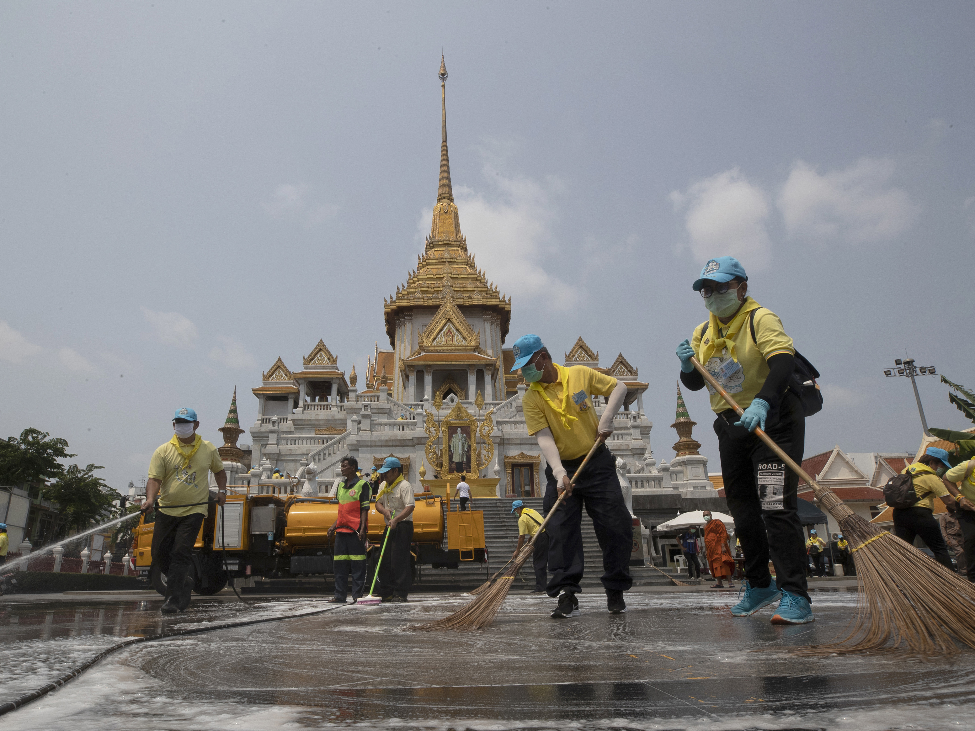 caption: Volunteers clean as a precaution against the new coronavirus at Wat Traimit temple in Bangkok, Thailand, on Wednesday. Thailand's government has enacted stronger measures to combat the spread of COVID-19.