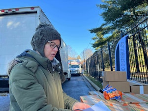 caption: Alysa MacClellan, 47, prepares to send volunteers to their designated drop offs at a food distribution site in Washington, D.C.