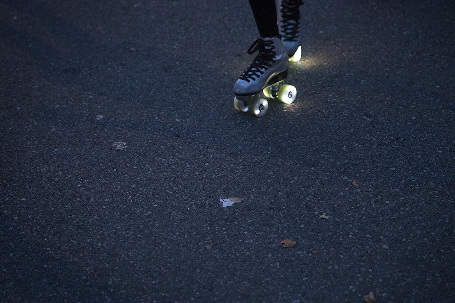 caption: Co-founder of Seattle Skates, Artemis Peacocke, skates with light-up wheels  as the sun goes down on Wednesday, September 30, 2020, along Alki Avenue Southwest in Seattle.