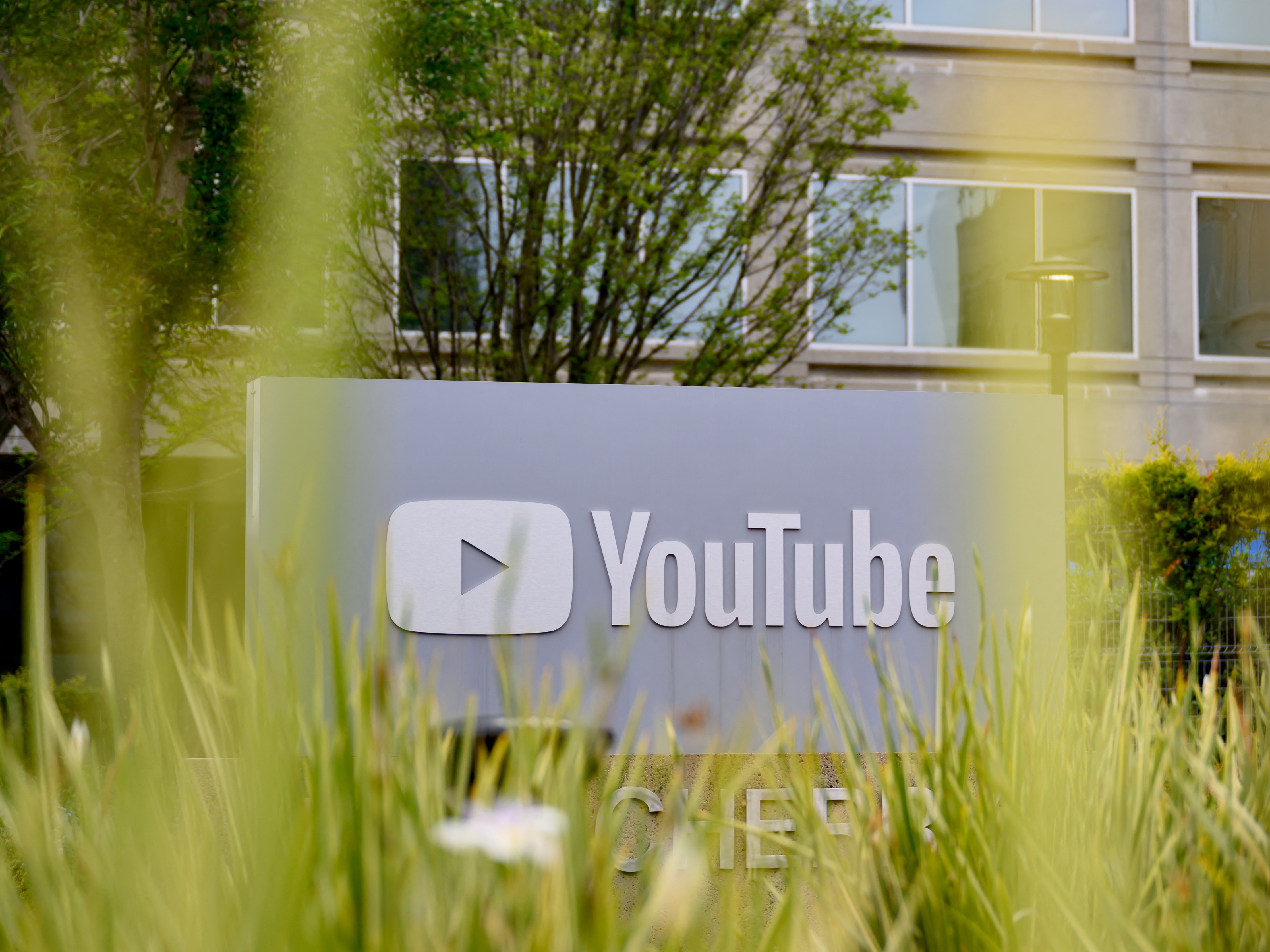 caption: The YouTube logo is seen outside the company's corporate headquarters in San Bruno, California, in April 2025. The company settled a lawsuit brought against it by President Trump before his re-election.