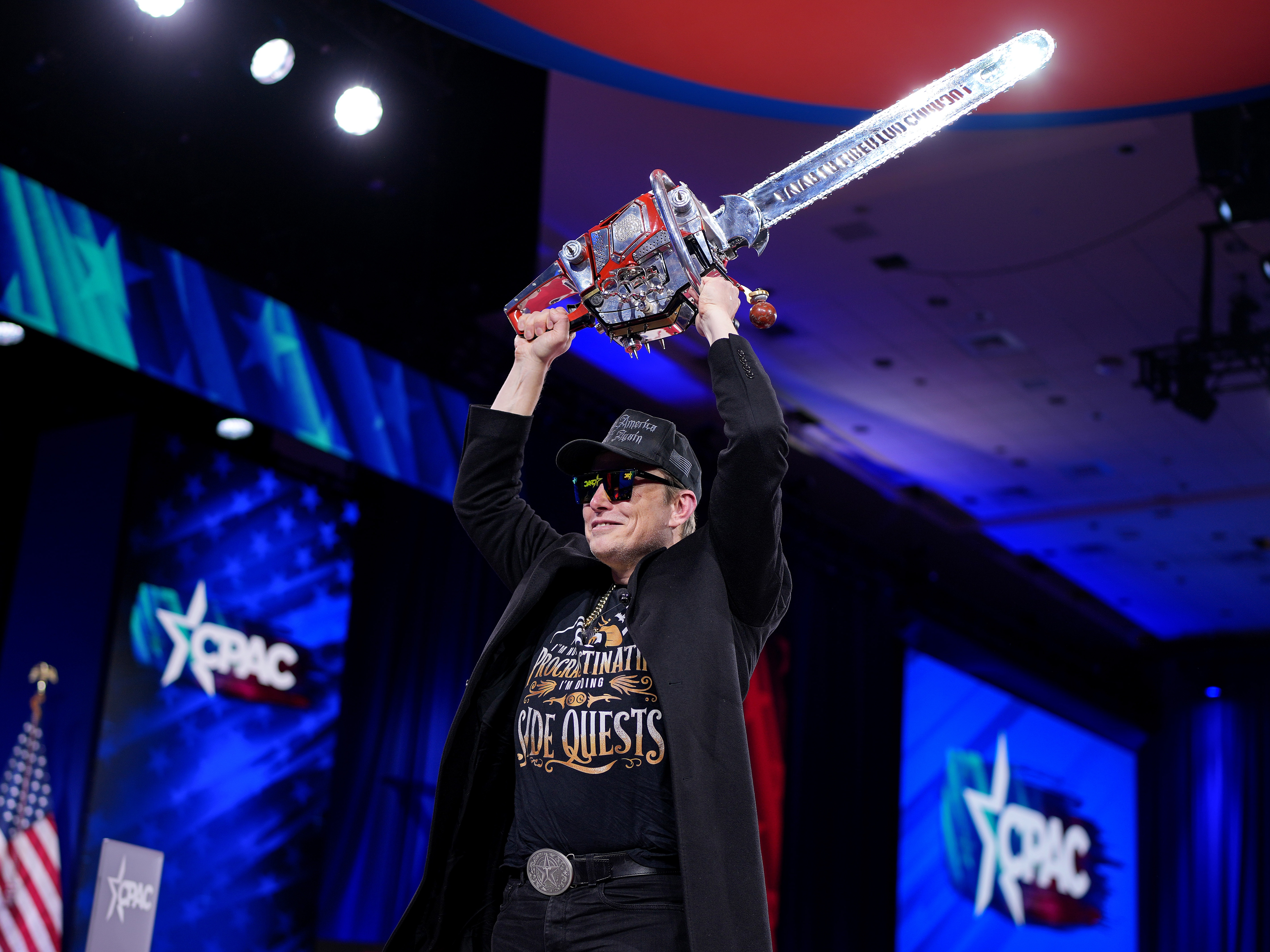 caption: Elon Musk wields a chainsaw at the Conservative Political Action Conference on Feb. 20 in Oxon Hill, Md.