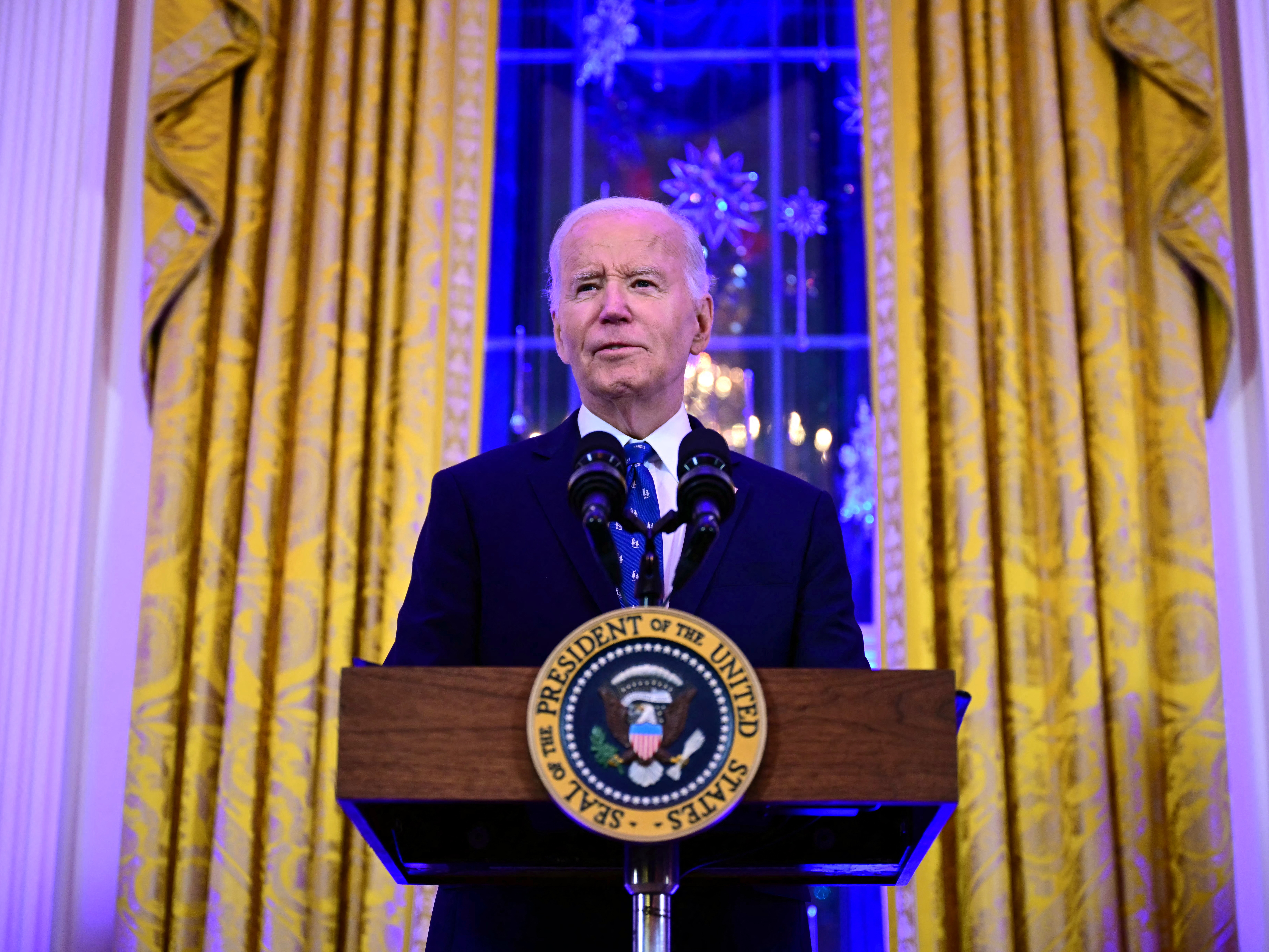 caption: President Biden speaks during a reception in the East Room of the White House on Dec. 16.