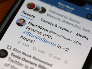 caption: In this photo illustration, businessman and Twitter owner Elon Musk tweets about a Twitter Spaces event he will be hosting with Florida Governor Ron DeSantis on May 24, 2023 in Chicago, Illinois.