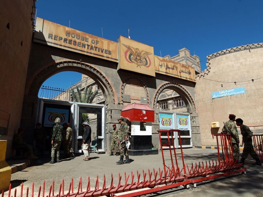 caption: Yemeni security guards stand outside the parliament building in Sanna in 2015, the same year that a Yemeni lawmaker says he was targeted for assassination. Anssaf Ali Mayo is now suing former U.S. military members who he says were hired to kill him.