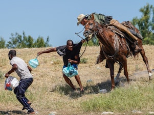 caption: A United States Border Patrol agent on horseback tries to stop a Haitian migrant from entering an encampment on the banks of the Rio Grande near the Acuna Del Rio International Bridge in Del Rio, Texas on Sept. 19, 2021.