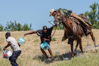 caption: A United States Border Patrol agent on horseback tries to stop a Haitian migrant from entering an encampment on the banks of the Rio Grande near the Acuna Del Rio International Bridge in Del Rio, Texas on Sept. 19, 2021.