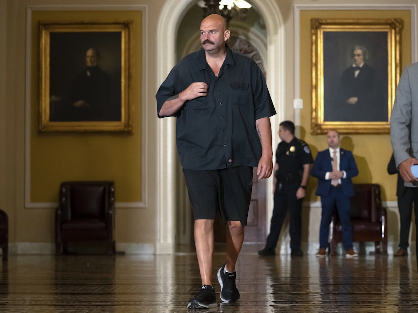caption: Sen. John Fetterman, D-Pa., walks on Capitol Hill on Thursday. He says he will continue to wear a suit on the Senate floor in compliance with the newly codified dress code.
