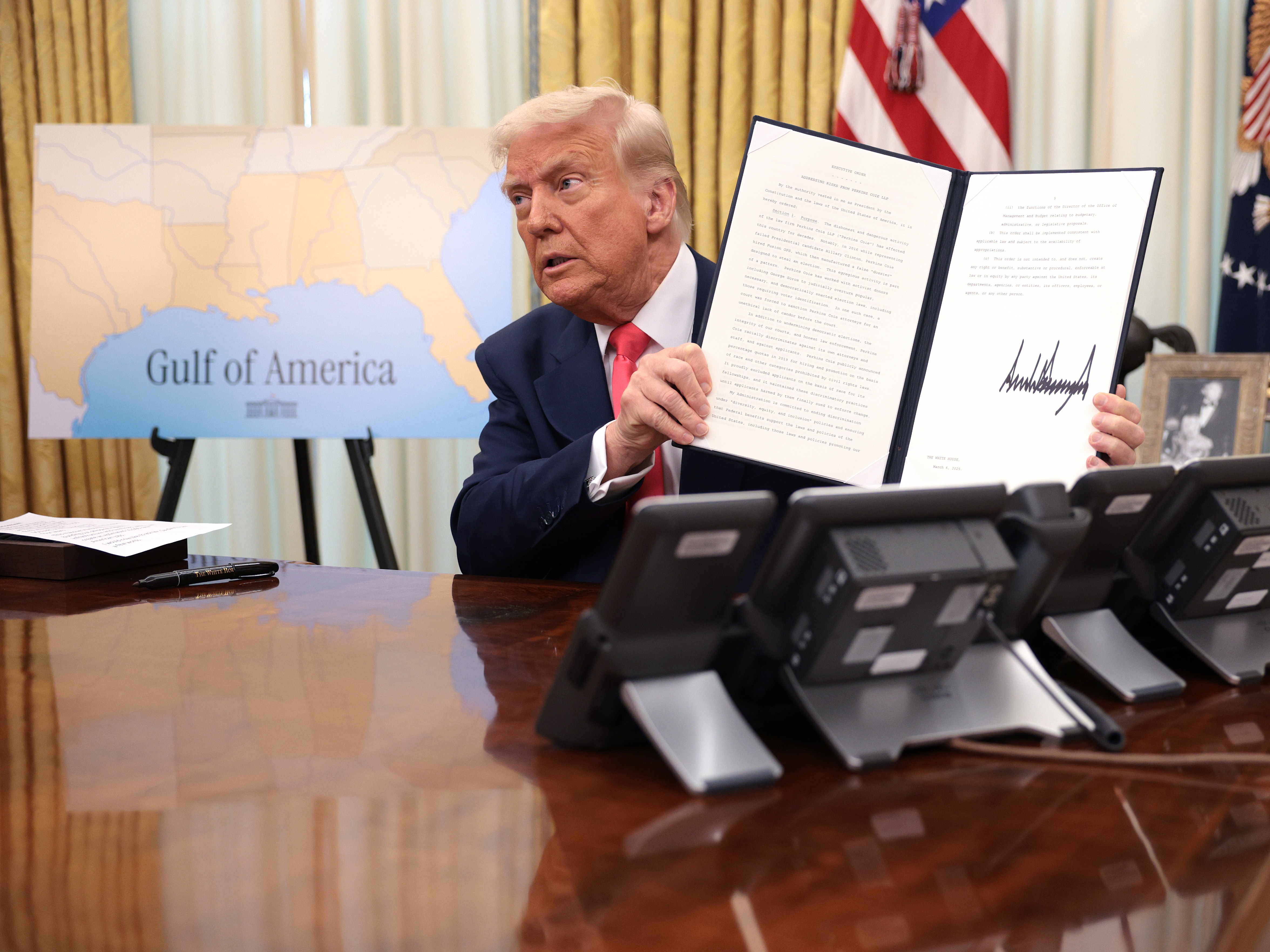 caption: President Trump signs executive orders in the Oval Office on March 6, including the order terminating the security clearances of those who work at the law firm Perkins Coie.