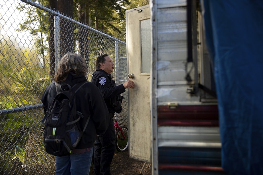 caption: Pam Paine, outreach coordinator at Olympic Peninsula Community Clinic, left, and Port Angeles code enforcement officer Derek Miller, right, check on an individual living in an R.V. and offer shelter options and services on Tuesday, April 25, 2023, in Port Angeles.
