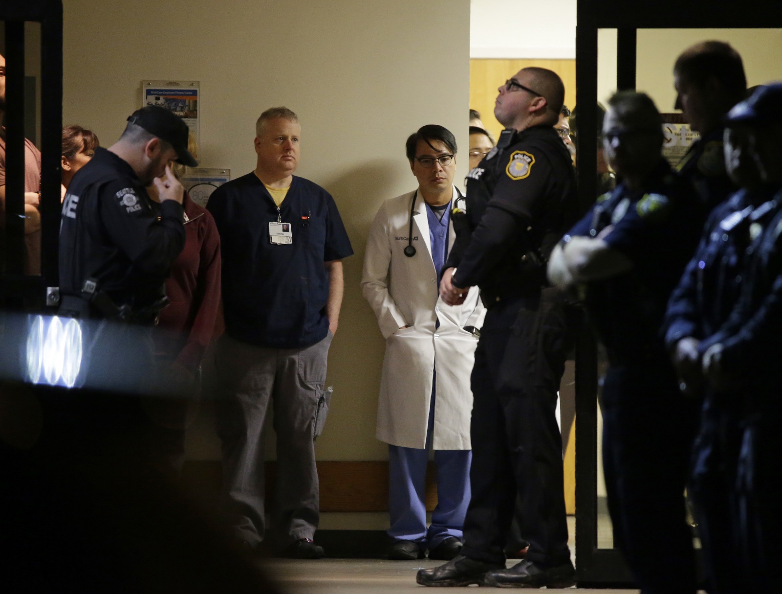 caption: Hospital and law enforcement workers stand at an entrance to Tacoma General Hospital in Tacoma, Wash., as they wait for the body of a Tacoma Police officer who was shot and killed while answering a domestic violence call Wednesday, Nov. 30, 2016.