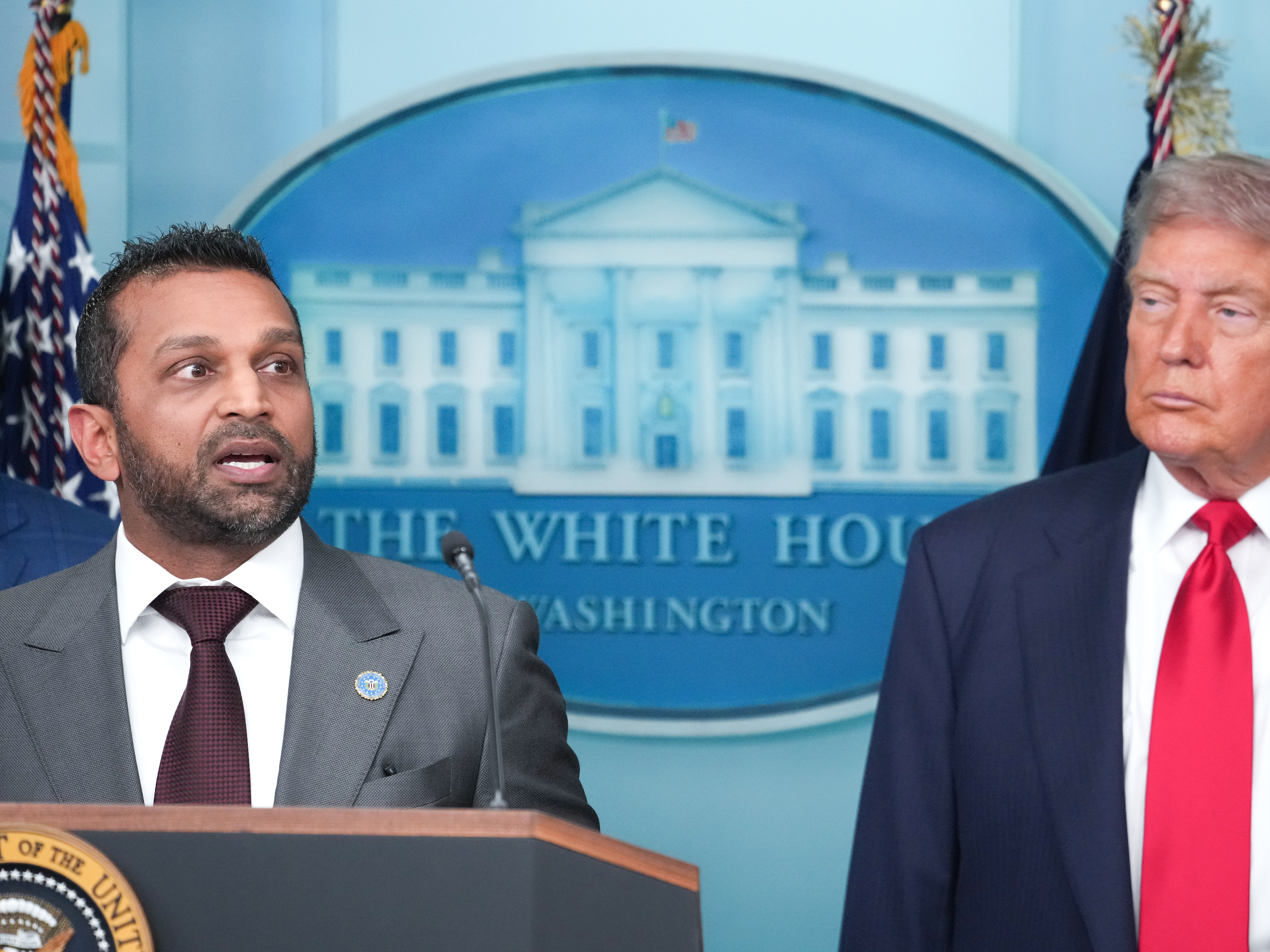 caption: FBI Director Kash Patel delivers remarks as U.S. President Donald Trump looks on during a White House press conference in August 2025.