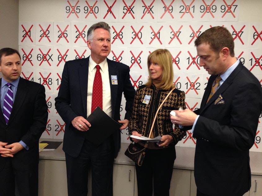 caption: From left, King County Councilmembers Rod Dembowski, Larry Phillips, Jane Hague and Joe McDermott prepare for a press conference. The poster behind them lists targeted bus routes.