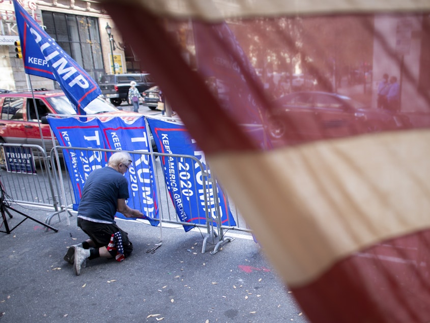 caption: A supporter of President Trump, fastens Trump campaign flags to a police barricade last week in Philadelphia.