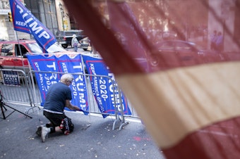 caption: A supporter of President Trump, fastens Trump campaign flags to a police barricade last week in Philadelphia.