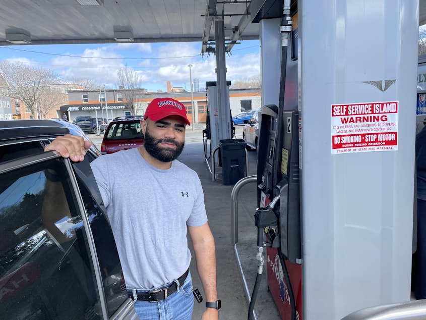 caption: Argenis Dominguez fueling up his SUV at a gas station in Boston. He drives Uber for a living and says the higher gas prices mean less money in his pocket.