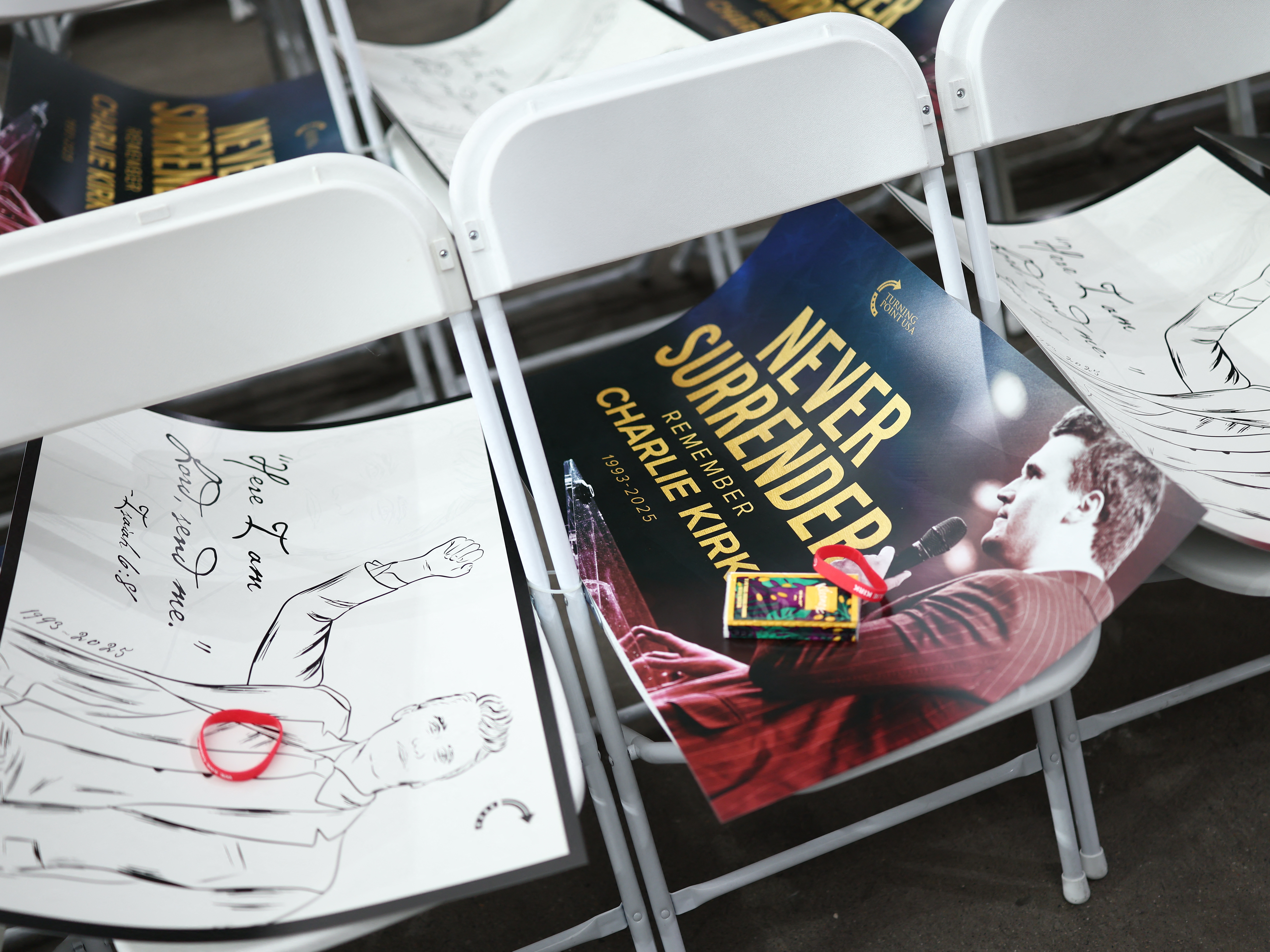 caption: Signs are seen on chairs ahead of the public memorial service of conservative activist Charlie Kirk at the State Farm stadium in Glendale, Ariz. on Sept. 21.