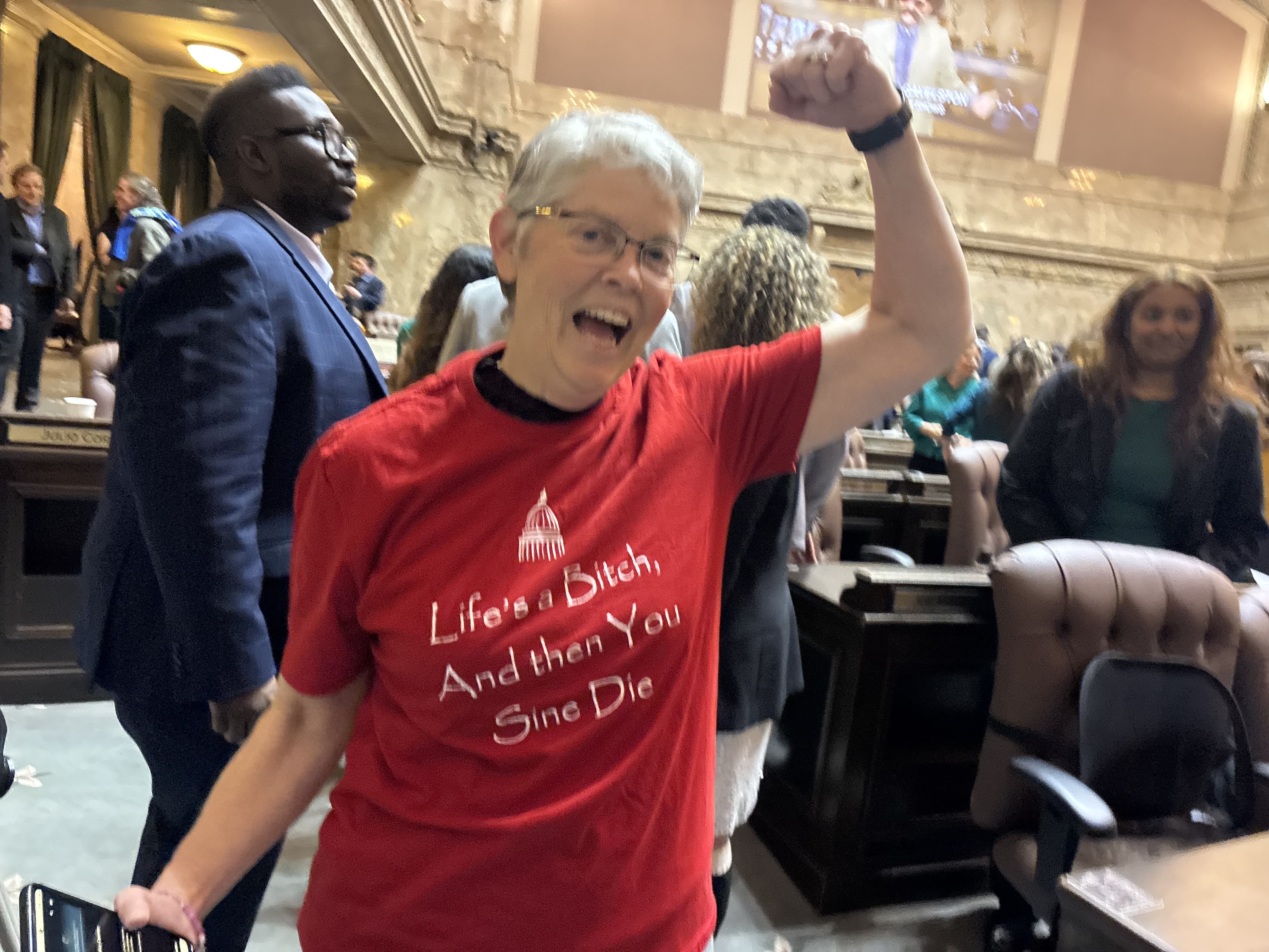 caption: Washington Speaker of the House Laurie Jinkins celebrates after the end of session with a joke t-shirt on March 12, 2026, at the state Capitol in Olympia.