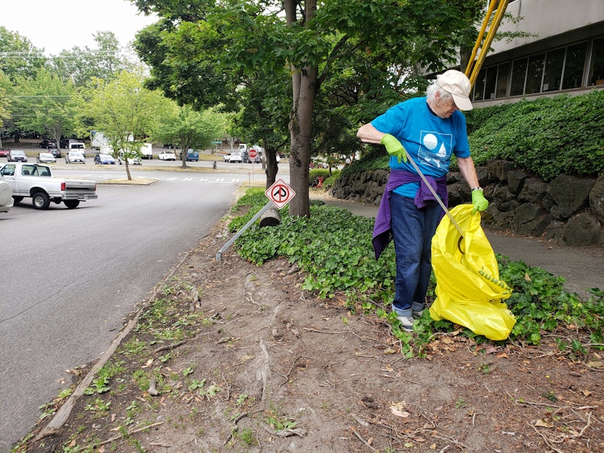 caption: Kathy Huntsman adds a bottle cap to her trash bag across the street from Gassworks Park. This is her fourth year cleaning up litter after the 4th of July fireworks show.