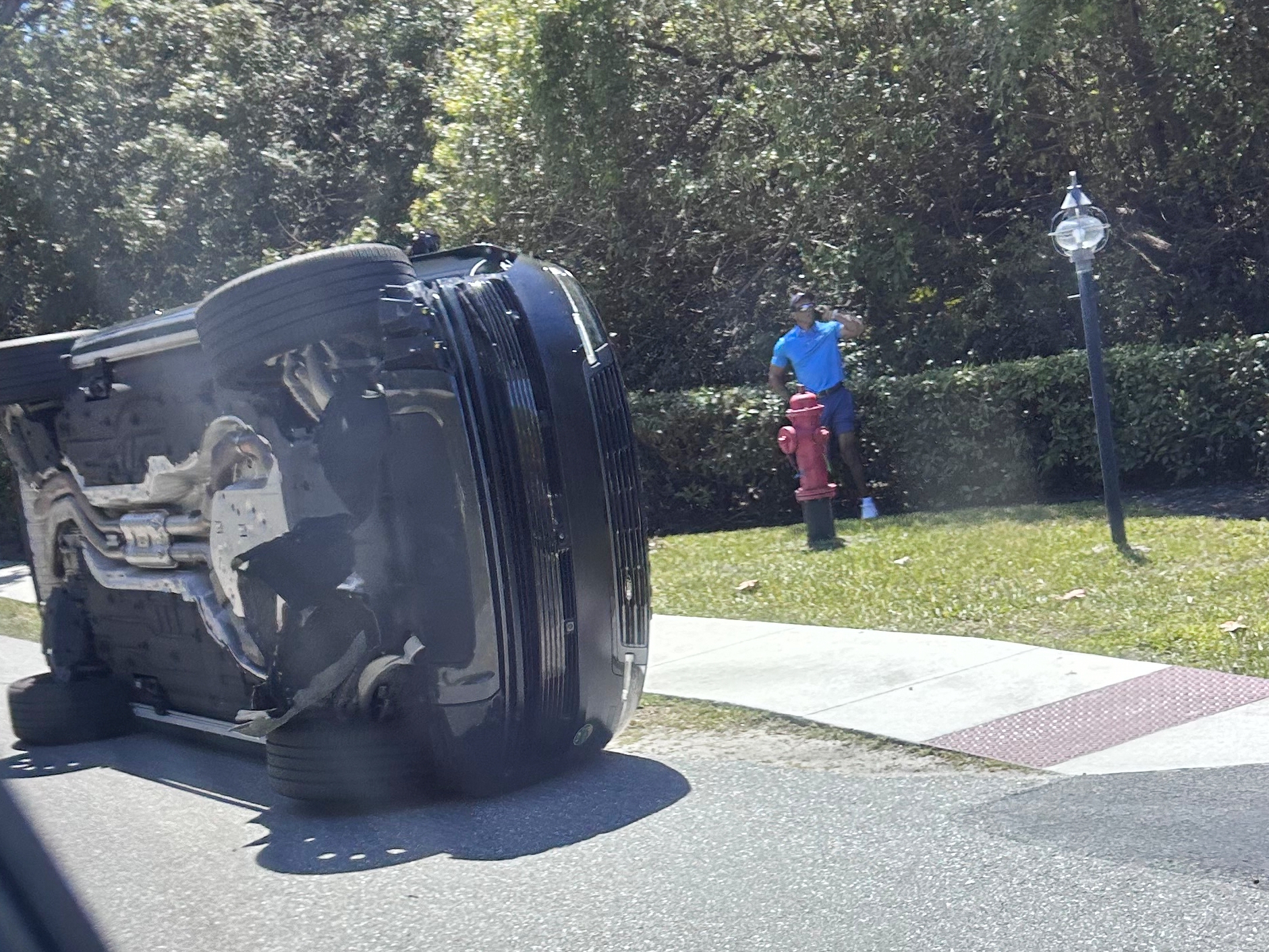 caption: Golfer Tiger Woods stands by his overturned vehicle in Jupiter Island, Fla., on Friday, March 27, 2026.