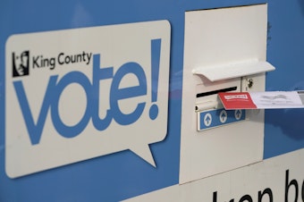caption: A person puts their ballot in a drop box on Oct. 27, 2020, at a library in Seattle. Under Washington state's primary system, the top two vote getters advance to the general election in November, regardless of party.
