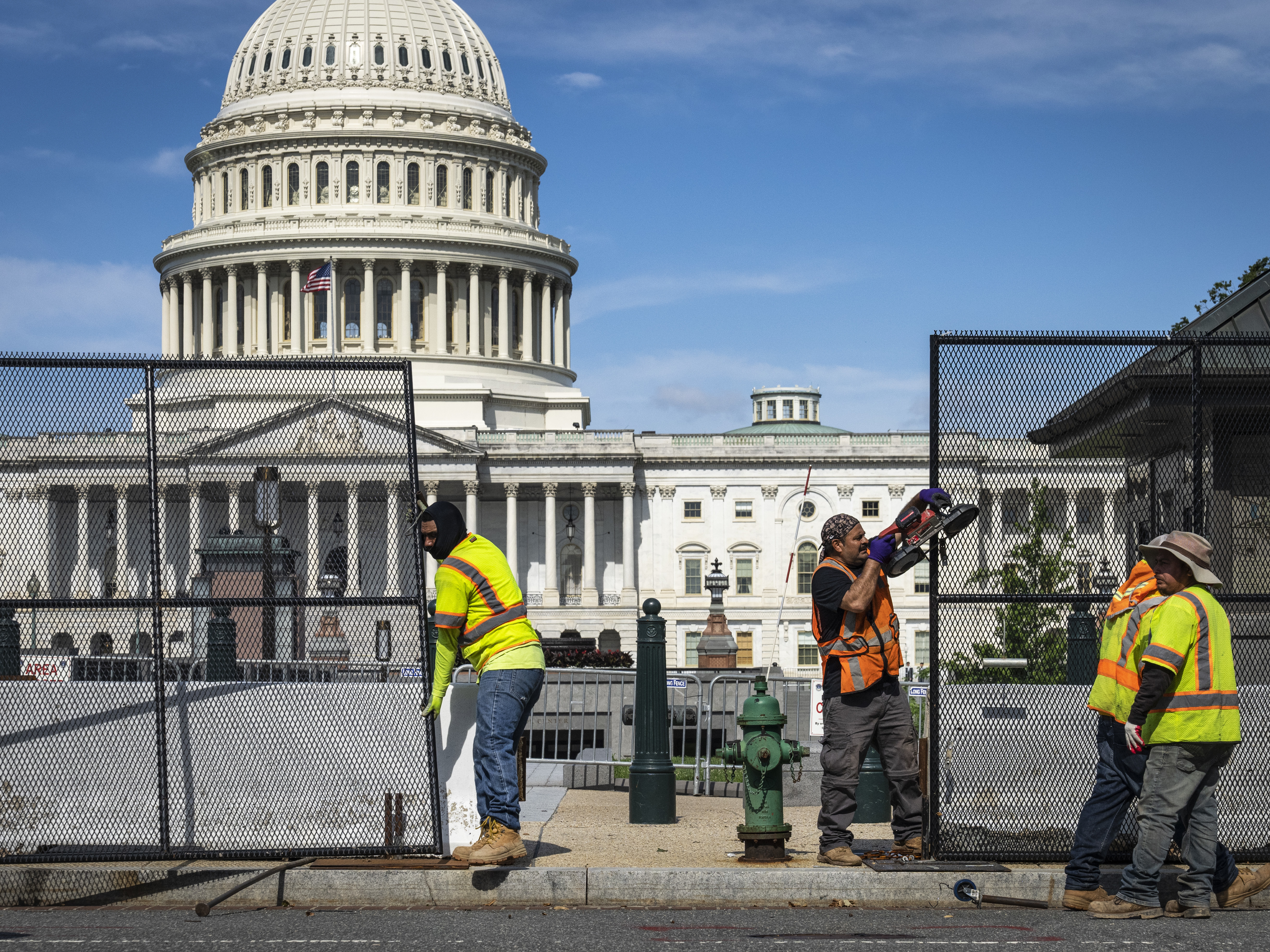 caption: Workers remove security fencing surrounding the U.S. Capitol on Saturday.