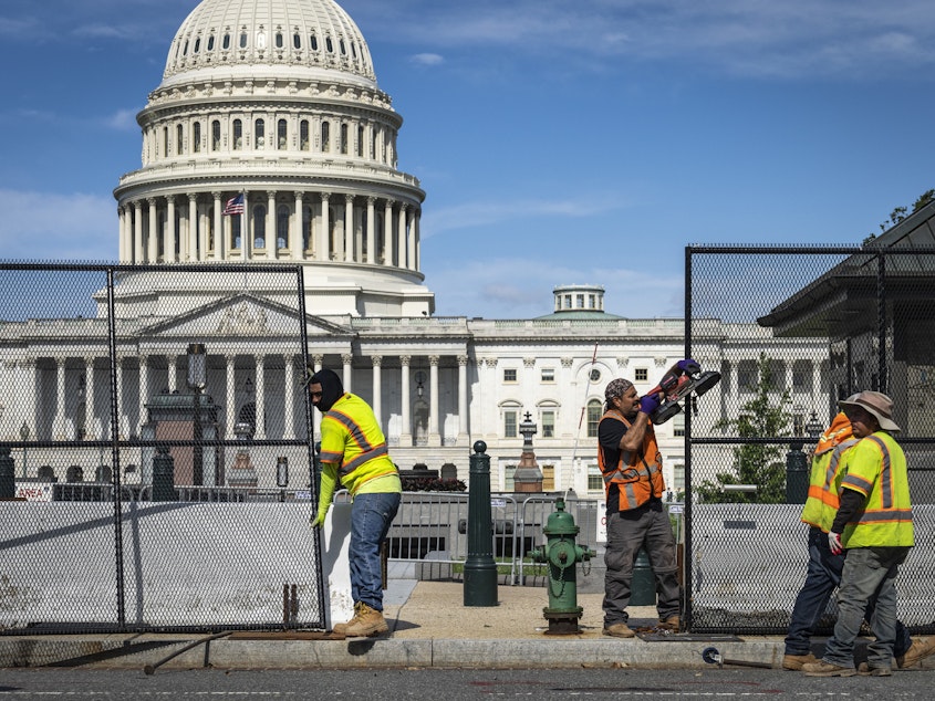 caption: Workers remove security fencing surrounding the U.S. Capitol on Saturday.