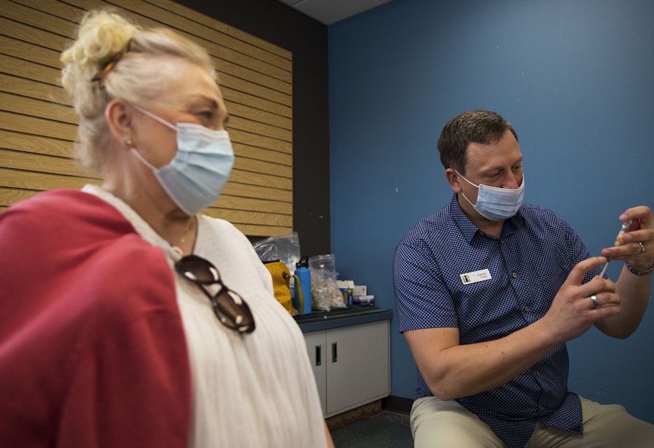 caption: Aaron Syring, owner and pharmacist at Island Drug, prepares to vaccinate Dawne'ne Jewett against Covid-19 on Wednesday, April 7, 2021, at Island Drug in Oak Harbor. Jewett drove from Langley to get the vaccine.