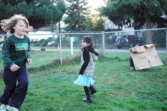 caption: Jorge (right) hides behind a cardboard while his sister and Ronan play with the dog.