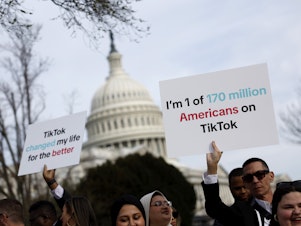 caption: People hold signs in support of TikTok outside the U.S. Capitol Building on March 13.