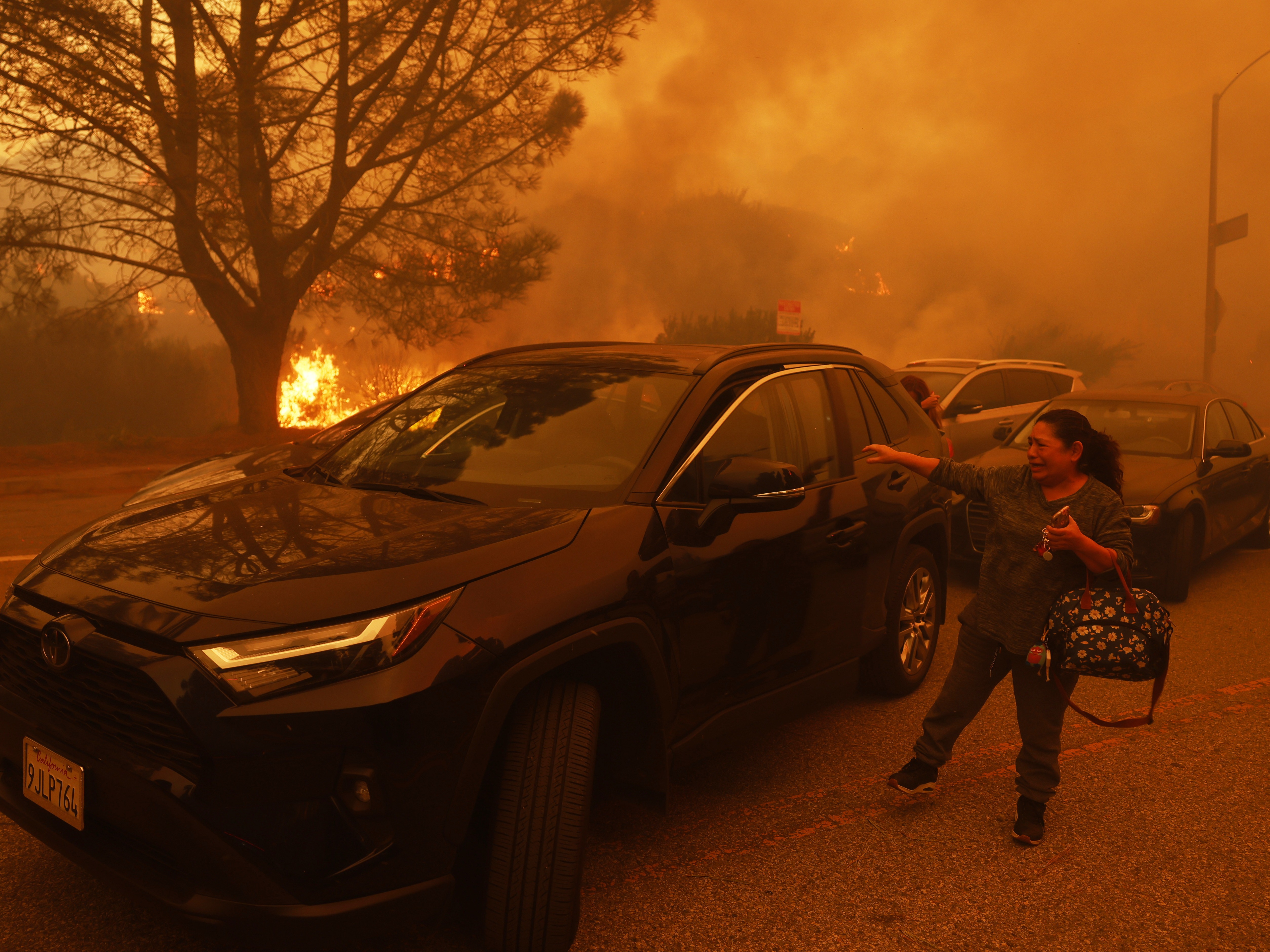 caption: A woman cries as the Palisades Fire advances in the Pacific Palisades neighborhood of Los Angeles on Tuesday.
