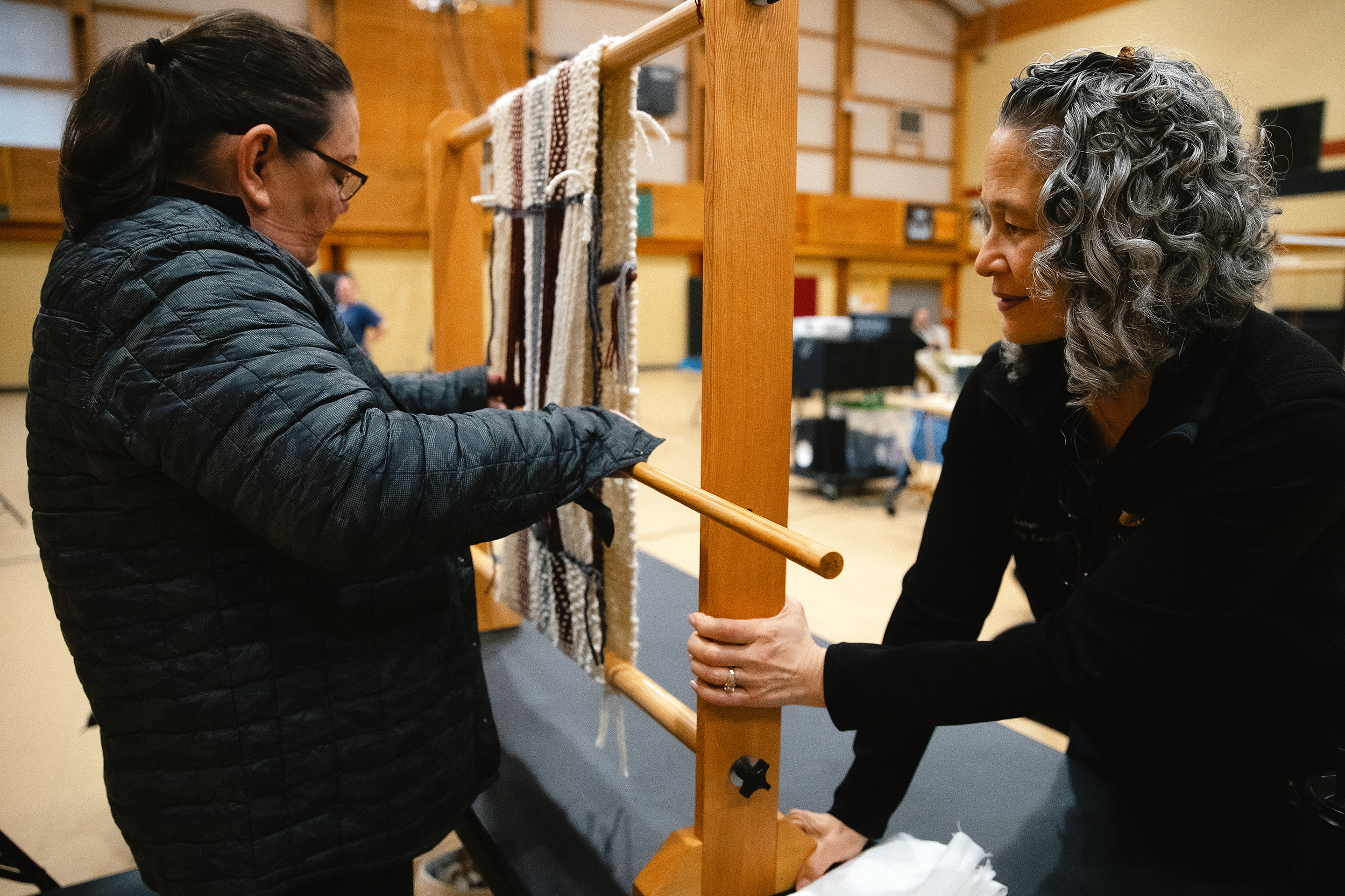 caption: Susan Pavel, instructor with the Coast Salish Wool Weaving Center, right, assists as student Lena Hammons removes her work from the loom, on Saturday, March 7, 2026, during a class at the Don Hatch Youth Center in Tulalip. 