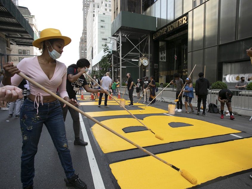 caption: Azia Toussaint helps paint a Black Lives Matter mural on Fifth Avenue in front of Trump Tower on Thursday in New York.