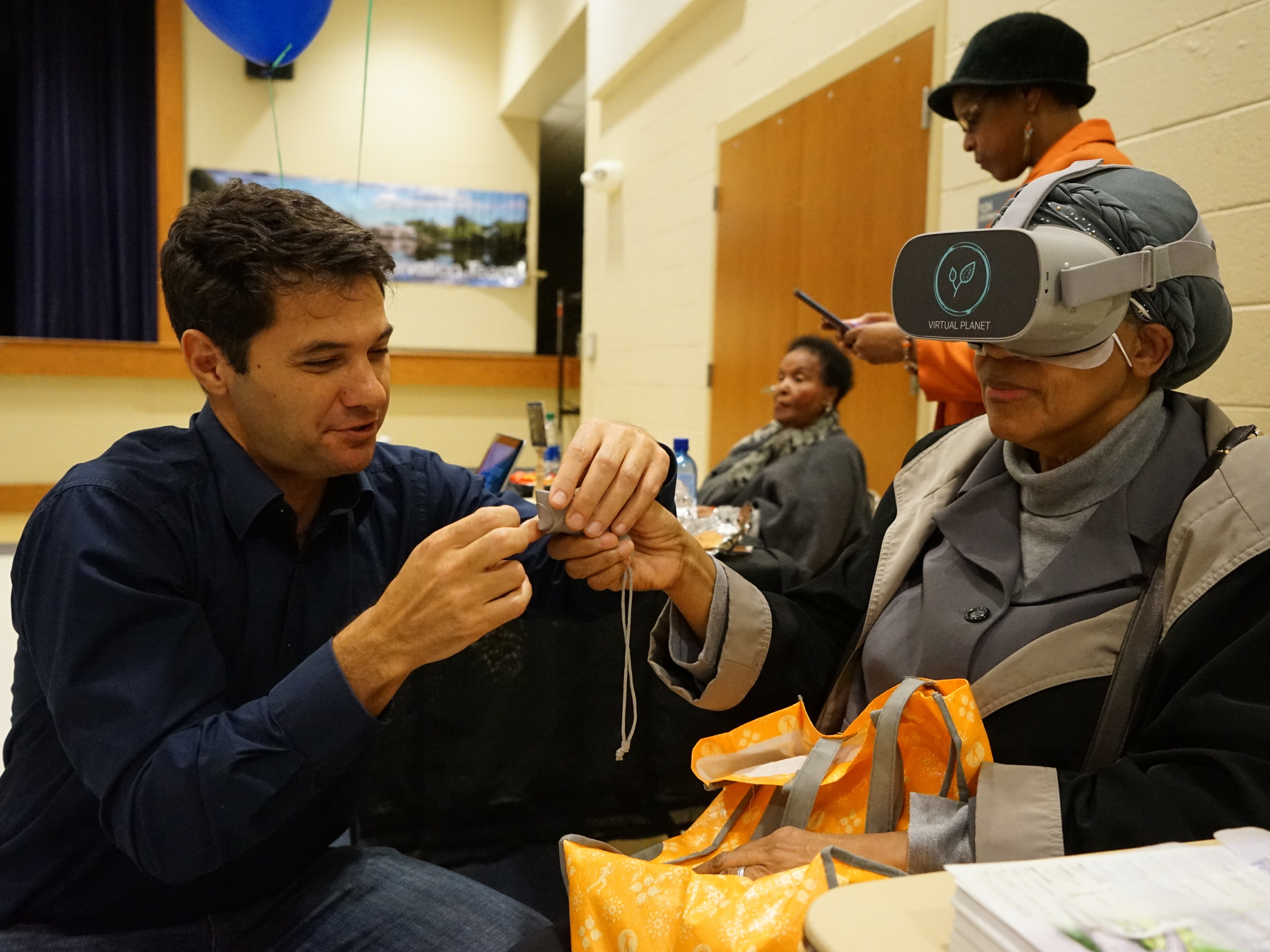 caption: Climate researcher Juliano Calil helps a resident of Turner Station use the virtual reality program he created to show the expected impacts of sea level rise there.