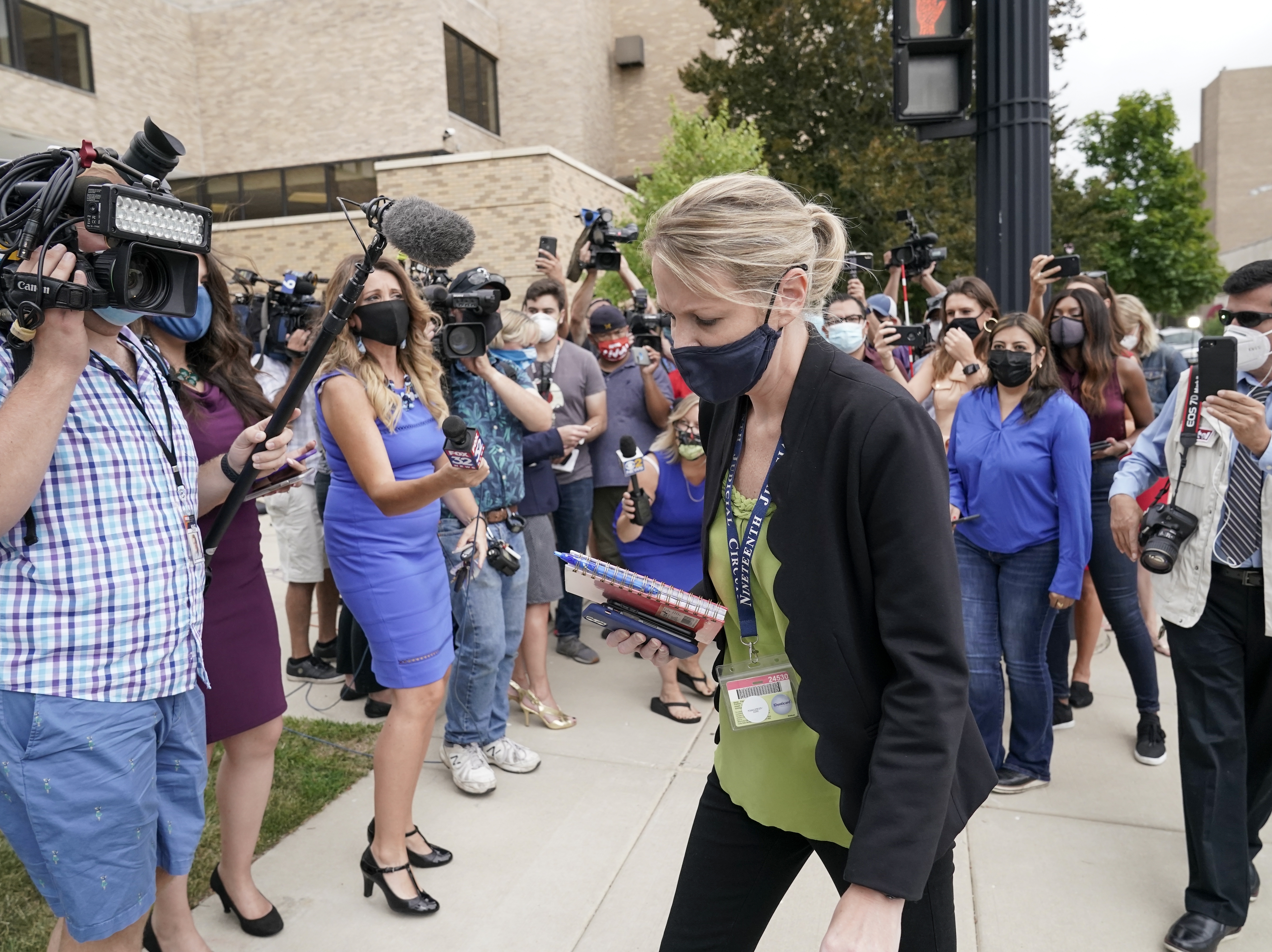 caption: Kasey Morgan, a public information officer for the Lake County Court, walks away from reporters outside the Lake County courthouse following the extradition hearing for Kyle Rittenhouse on Friday in Waukegan, Ill.