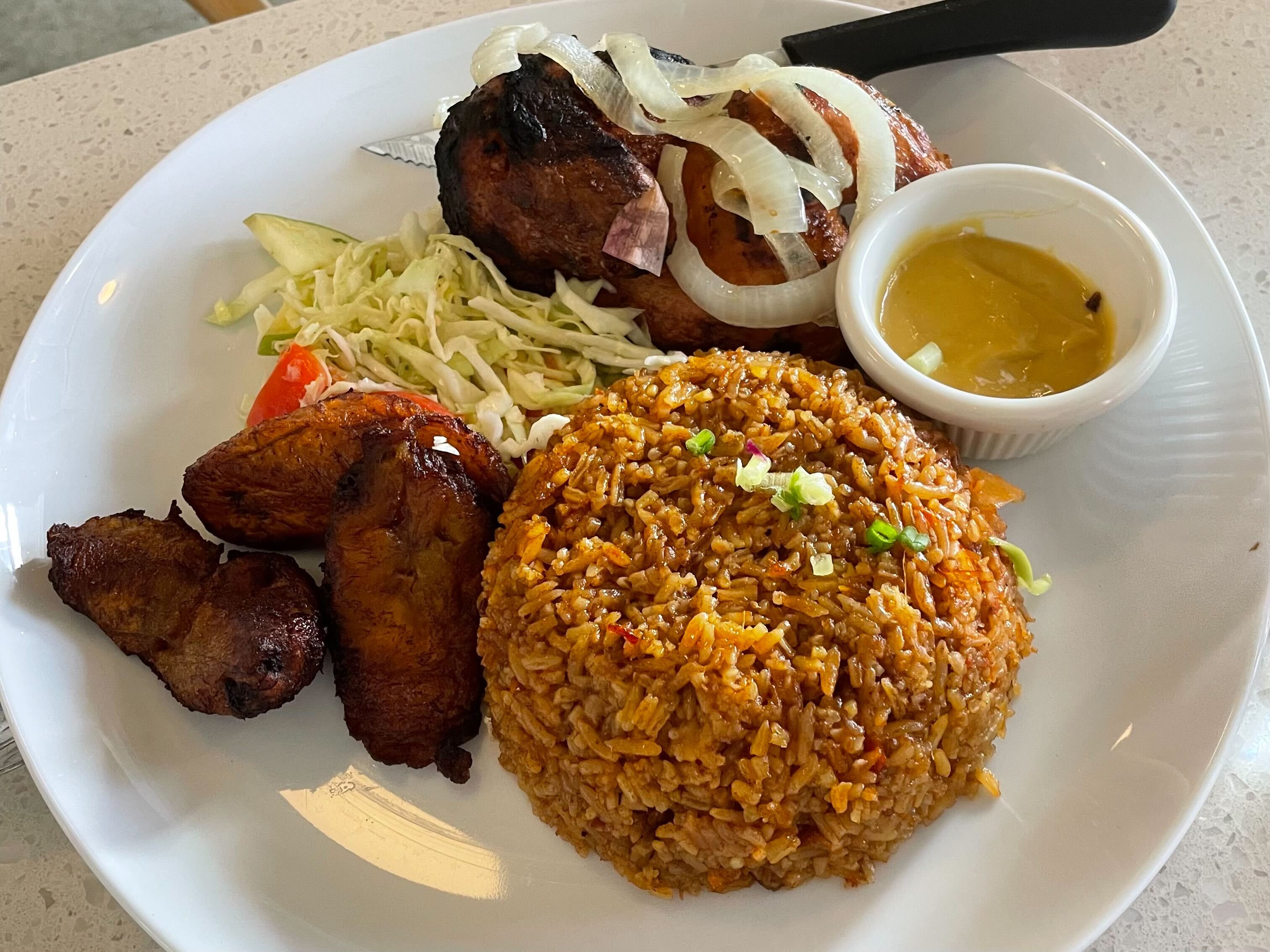 caption: A jollof rice plate with grilled chicken and plantain from Gold Coast Ghal Kitchen on First Hill in Seattle.