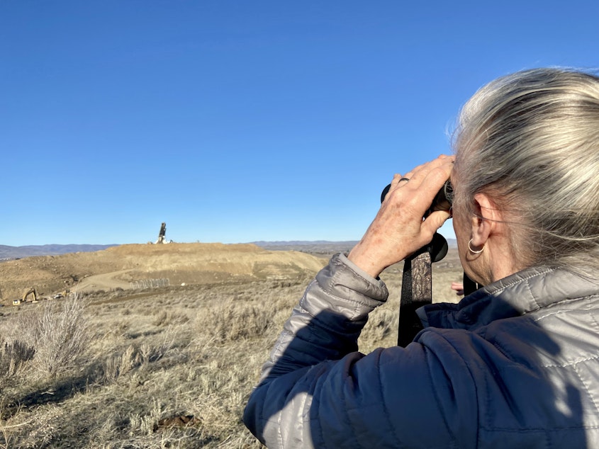 caption:  While hiking, Nancy Lust, with Friends of Rocky Top, watches a truck dump waste into a landfill in Yakima County. Lust lives near the landfill and has fought to learn more about what's getting disposed of near her home.