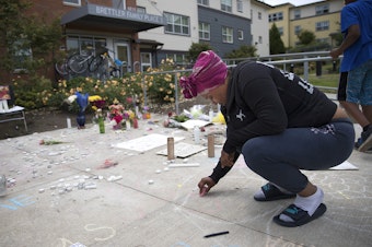 caption: Alaina Williams, a friend and neighbor of Charleena Lyles, writes, 'Love U Leena,' in chalk at a memorial for Lyles on Monday. 