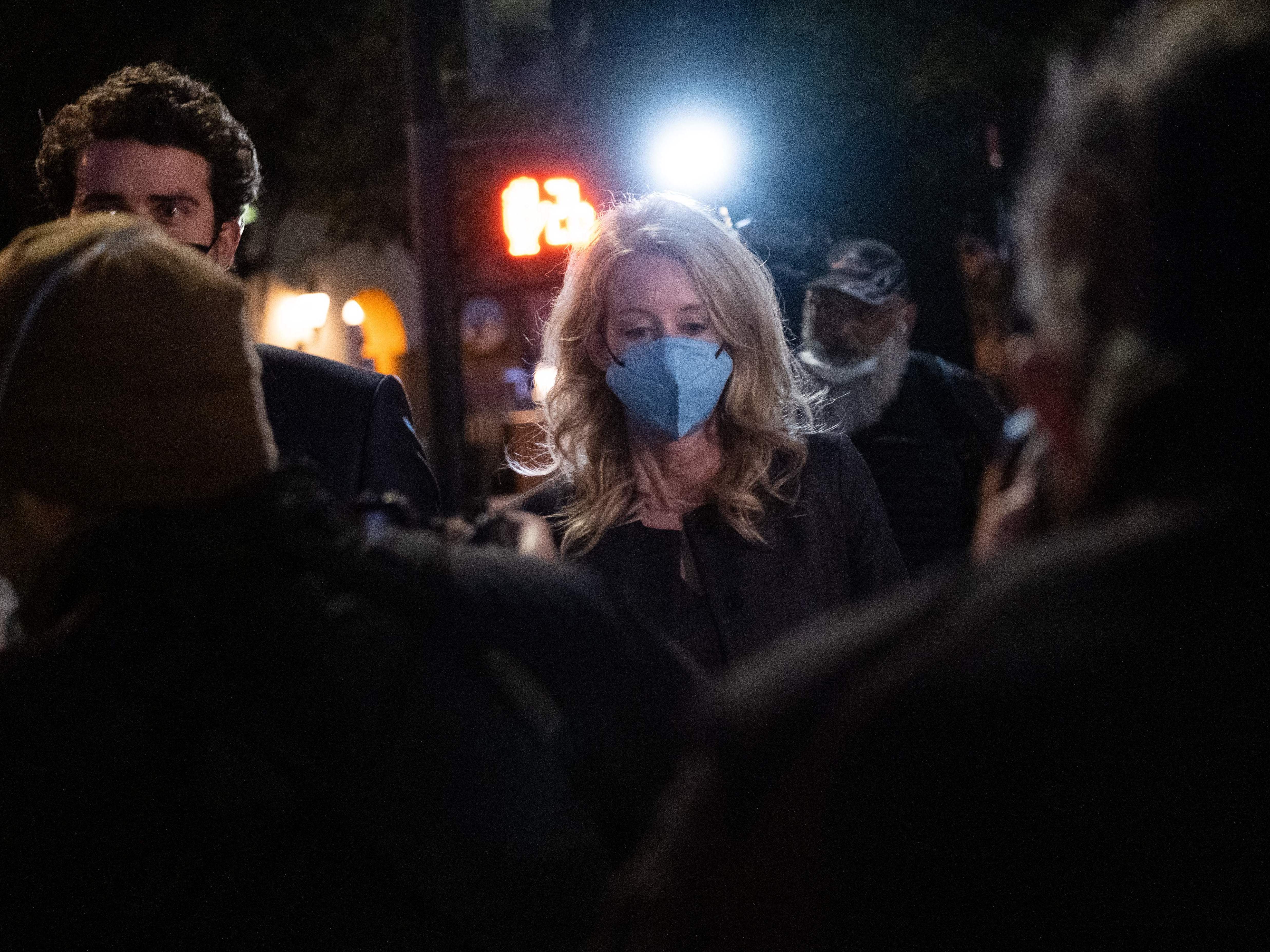 caption: Elizabeth Holmes and partner Billy Evans walk outside the federal court in San Jose, California on January 3.