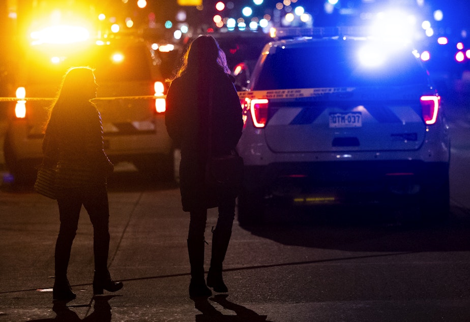 caption: People walk past the Sol Tribe tattoo shop where two women were shot and killed and a man injured on Dec. 27, 2021 in Denver, Colorado. It was the first in a series of shootings that claimed five lives across the area.