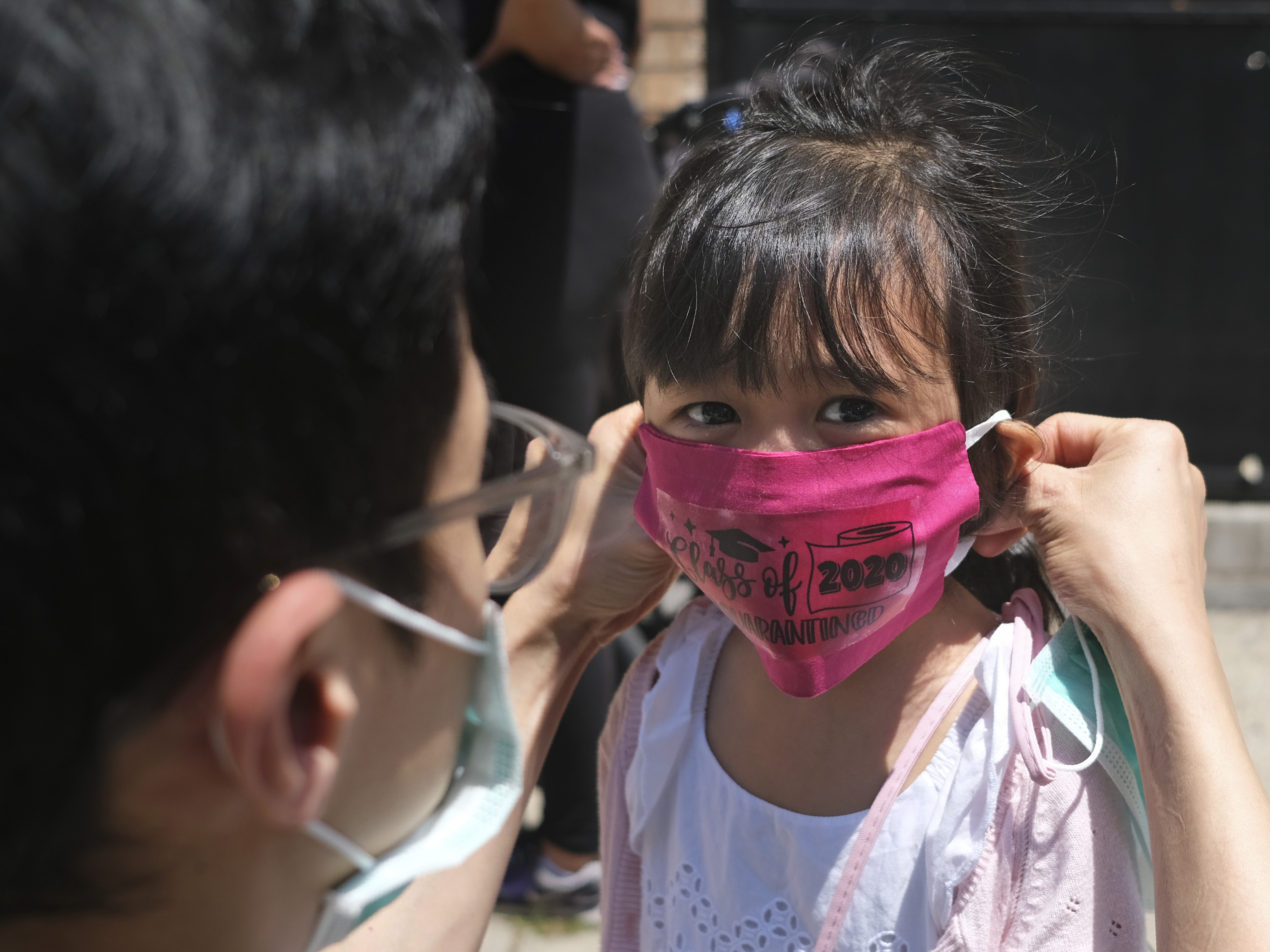 caption: A girl in Jersey City wears a mask at her Pre-K graduation ceremony almost a year ago. Now schools are deciding how looser CDC guidelines on masks affect education.