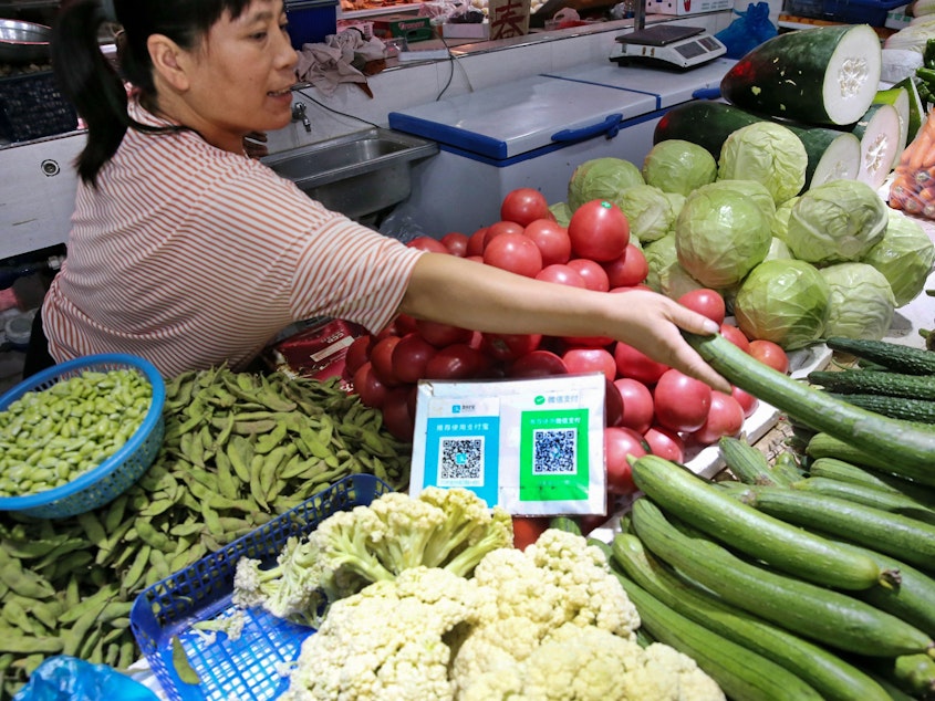 caption: Alipay and WeChat QR codes for online payment are displayed at a vegetable stall in Nantong in China's eastern Jiangsu province. Now the country's central bank is preparing to test a digital currency.